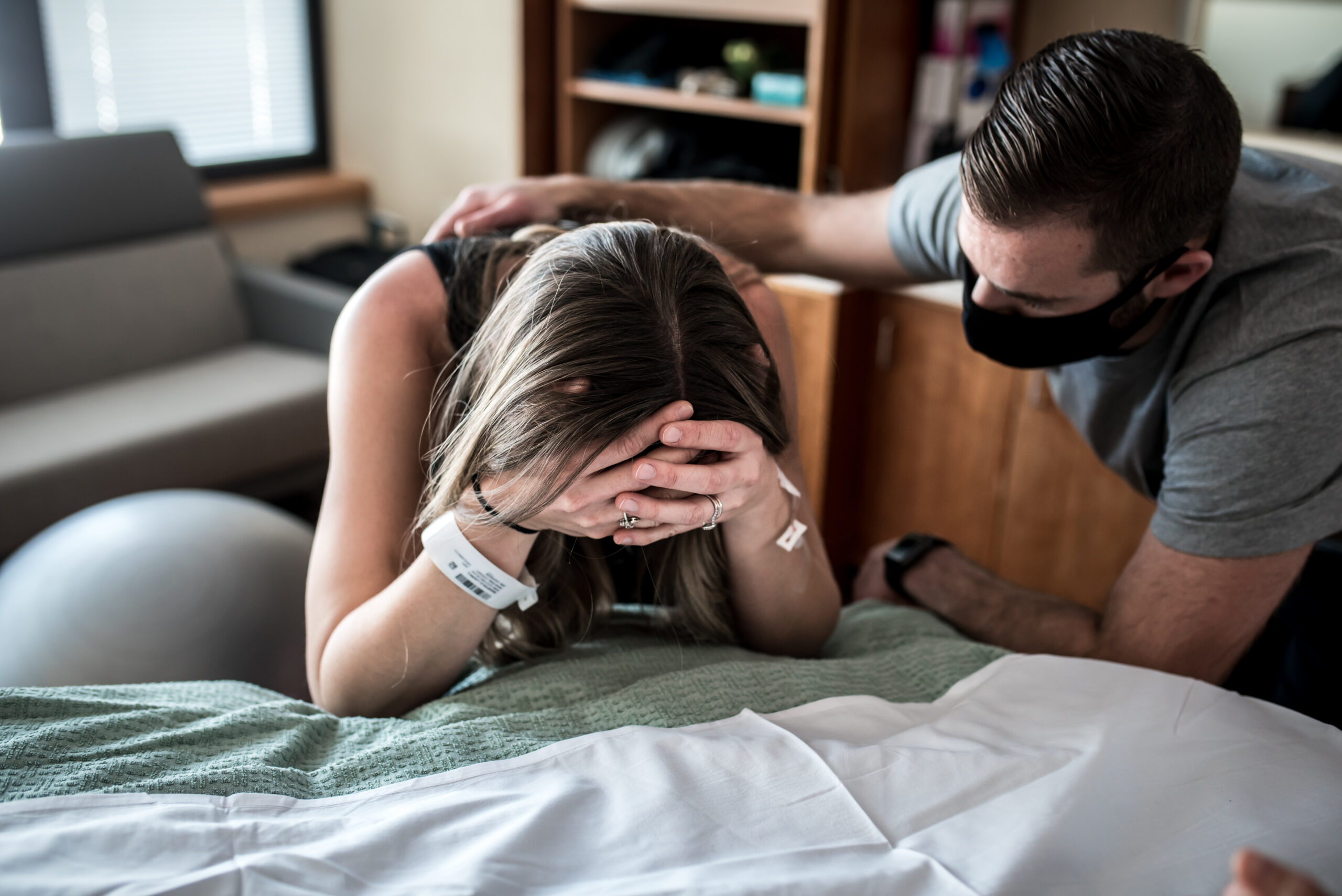 women in unmedicated labor over hospital bed
