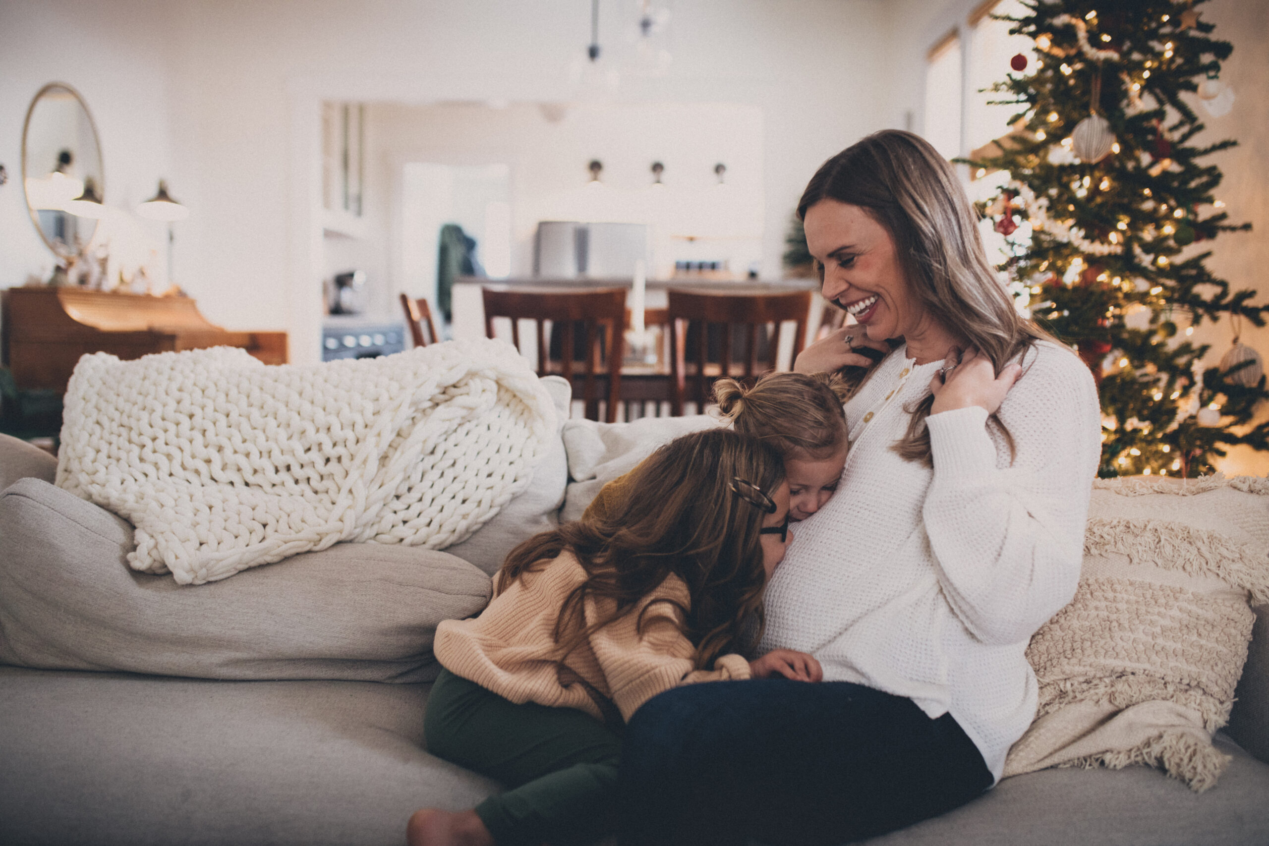 pregnant mom and daughters kissing her belly