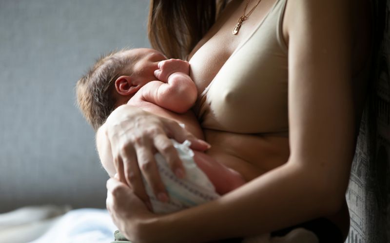 mother breastfeeding newborn baby in diaper