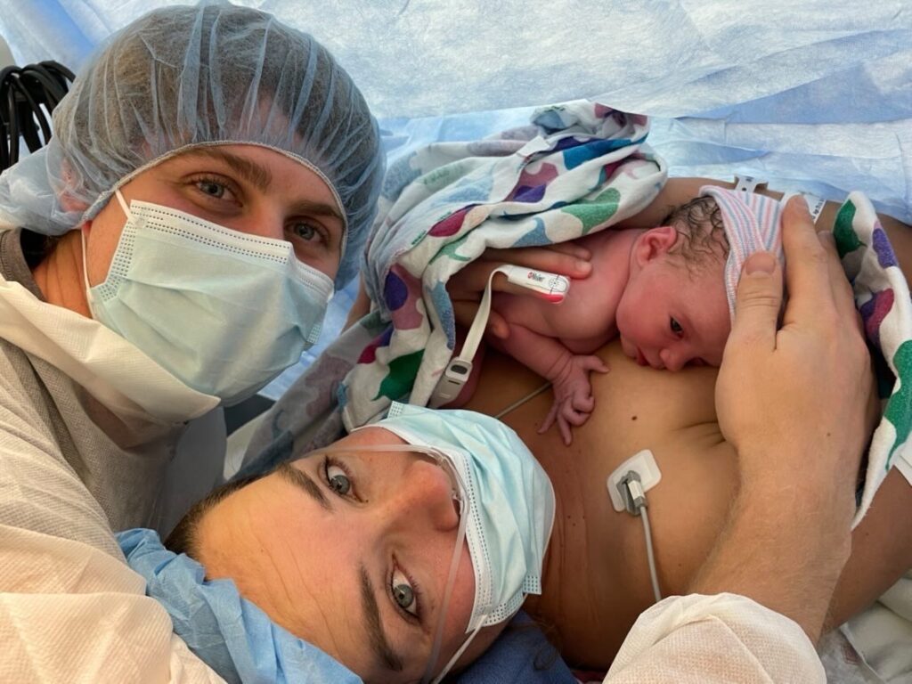 mother and father holding baby in operating room after cesarean birth
